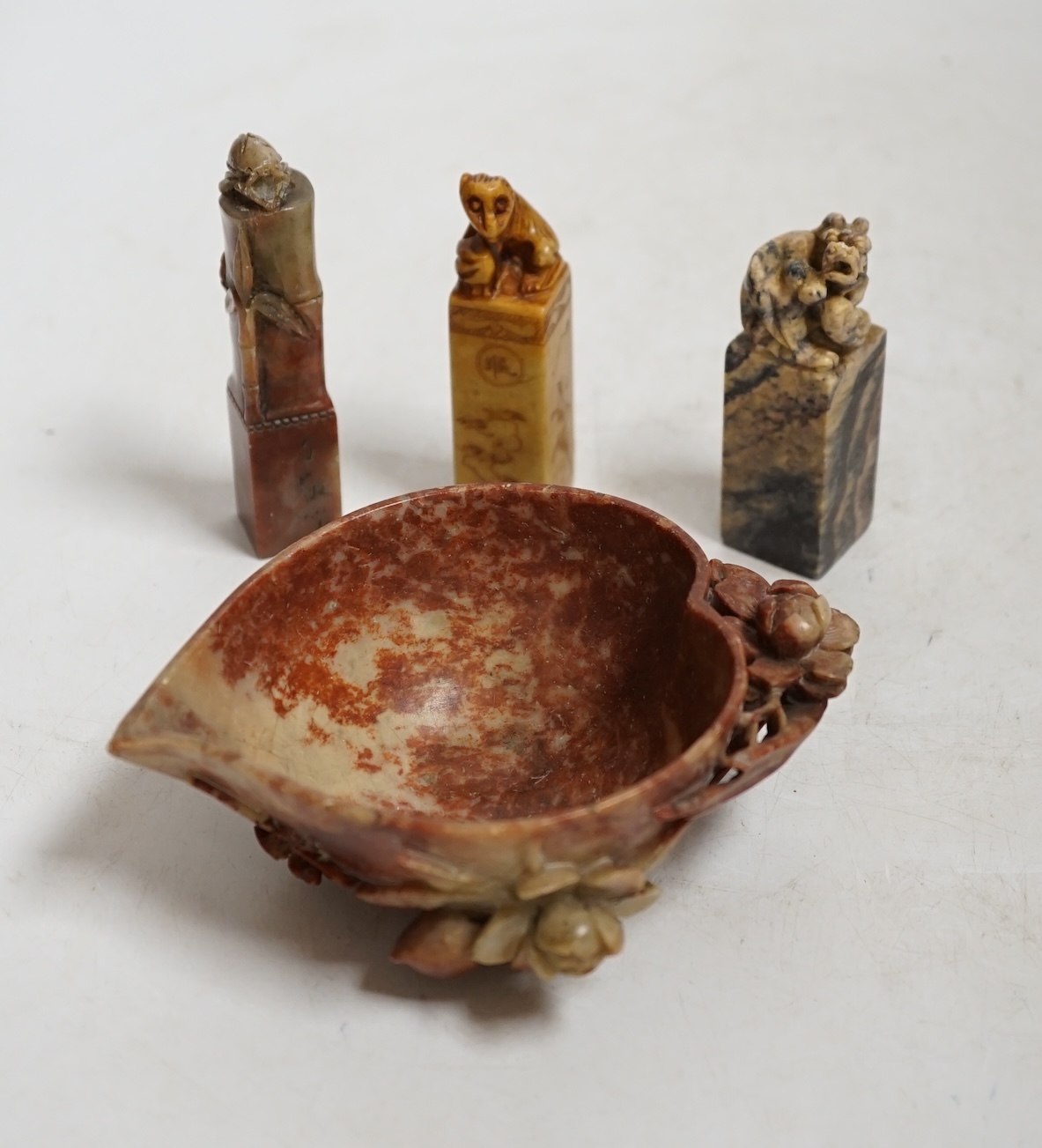 Three Chinese carved soapstone seals and a 'peach' cup, largest 12.5cm wide. Condition - fair to good